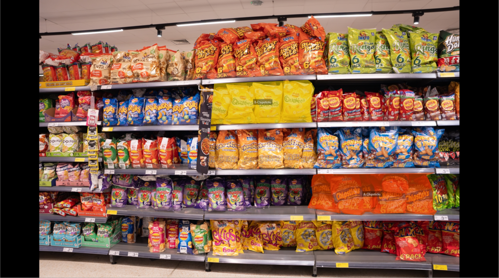 Crisps on shelves in a supermarket aisle.